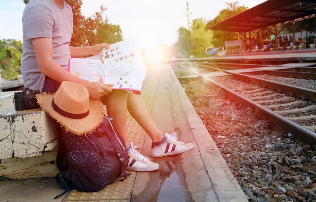 Overcome Hyper-Independence Through Solo Travel Person sitting at train station platform reading map, embracing travel adventure.